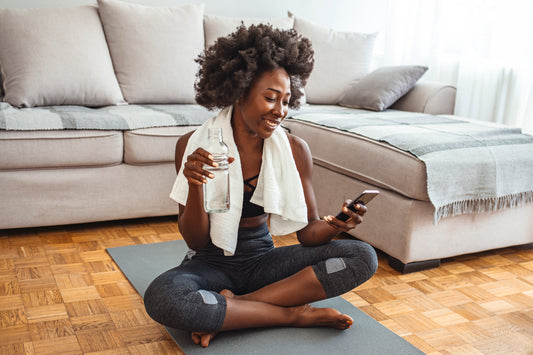 Black woman on the floor drinking Majiu Pure Alkaline Water 9.5